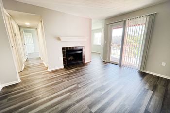 An empty living room with a fireplace and a sliding glass door
